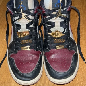 Nike Air Jordans i svart och vinrött - Snygga Nike Air Jordans i svart och vinrött med gulddetaljer. Skorna har en klassisk design med snörning och en vit sula. Perfekta för den som vill ha en stilren look med en touch av lyx. Skadda under skorna ser man på sista bilden men inget som påverkar skon eller något där av priset! Priset går att diskuteras vid snabb affär 