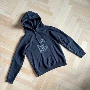 Saint Laurent Hoodie - Svart Saint Laurent hoodie i storlek herr Small.  Funkar även som dam M. Bra skick förutom att ett av hålen på huvan saknar sin metallknapp. Tveka inte på att skriva ifall du undrar nått!