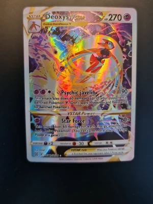 Pokémonkort Deoxys VSTAR holo - Säljer ett Pokémonkort med Deoxys VSTAR, holografisk yta med färgglada effekter. Kortet har attacker som Psychic Javelin och Star Force. Perfekt för samlare eller Pokémon TCG-spelare som vill ha en cool och kraftfull VSTAR i sin lek.