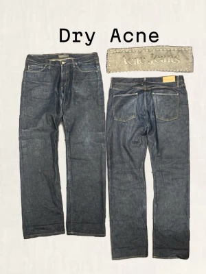 Mörkblå raka jeans från Acne - Säljer ett par mörkblå jeans från Acne med rak passform och klassisk femficksdesign. Jeansen är tillverkade i rå denim och har subtila kontrastsömmar. Perfekta för dig som gillar stilrena och tidlösa jeans.