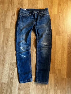 Dondup Monroe  - Säljer ett par mörkblå dondup jeans med slitningar och tvättade detaljer. Materialet är denim i bomull med stretch för extra komfort. Perfekta för att ha nu i höst.