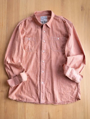Coral Workers Shirt, size XXL - Säljer en korall skjorta i linne från JMY DEE. Skjortan har två bröstfickor med knapp, klassisk krage och vita knappar framtill. Perfekt för dig som gillar en avslappnad men snygg stil. Storlek XXL.