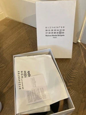 Maison Margiela sneakers med box - Maison Martin Margiela sneakers i originalförpackning med dustbag och äkthetskort. Klassisk design med minimalistisk look. Färg och material framgår ej tydligt på bilderna men box och tillbehör ingår.