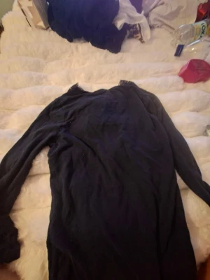 Mörkblå långärmad tröja med spets - Mysig mörkblå långärmad tröja med v-ringning och dekorativ spetskant vid halsen. Tröjan har en smal passform och är perfekt för dig som gillar en enkel men ändå lite elegant stil.
