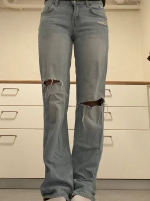 blå baggy jeans från Zara med hål  - Säljer ett par ljusblå jeans med hål över knäna. Dessa jeans är i bra sick men säljer p.g.a att dem är lite för små💕💕