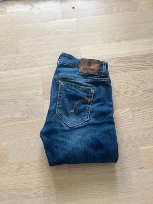 Blå jeans från Dondup - Snygga blå jeans från Dondup med klassisk femficksmodell och diskreta slitningar. Jeansen har raka ben och en patch med logga bak i midjan. Perfekta till en avslappnad stil och funkar året runt. W29 L30