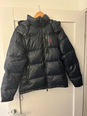 Ralph lauren Jacka - Säljer nu denna marinblåa Ralph lauren jackan som är mycket användbar nu inför dem kommande månaderna. Skicket på jackan är väldigt bra och inga defekter, dock har ena armens kardborre blivit lite lösare i sitt fäste när man drar över men det är inget märkvärdigt        Hör jättegärna av dig vid funderingar samt prisförslag som inte är helt bortom vettet!😊