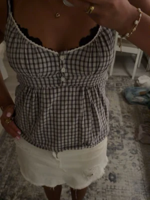 Sött linne från brandy Melville - Söt rutig linnetopp med smala axelband och knappar framtill. Toppen är använd fåtal gånger men jättefin. Storleken är XS/S och är svart och vit