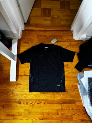 Svart Norge Nike träningströja - Snygg svart träningströja från Nike med Norge-tryck och diskret emblem på bröstet. Tillverkad i ett lätt och ventilerande funktionsmaterial som passar perfekt till träning eller sportaktiviteter. Klassisk rund hals och korta ärmar.