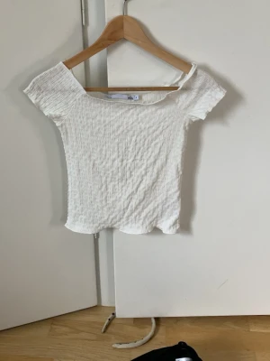 Vit ribbad topp från 157 - Säljer en vit ribbad topp från 157 med korta ärmar och stretchigt material. Toppen har en enkel, croppad passform och är perfekt för dig som gillar en clean och stilren look. Passar till allt och är superenkel att styla.