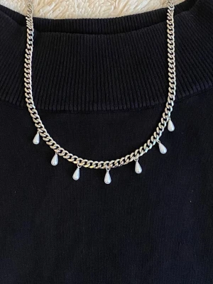 Silverfärgat halsband med pärldroppar - Säljer ett snyggt halsband i silverfärg med kedja och sju små droppformade pärlor som hänger längs kedjan. Perfekt för att ge din outfit en elegant touch. Passar till många olika stilar och är lätt att matcha med andra smycken.