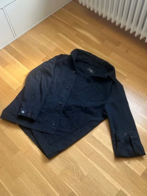 John henric overshirt - Stilren mörkblå overshirt från John Henric i bomull. Skjortjackan har knäppning framtill, bröstficka och manschetter med knappar. Perfekt lager-på-lager-plagg med avslappnad passform och klassisk krage.