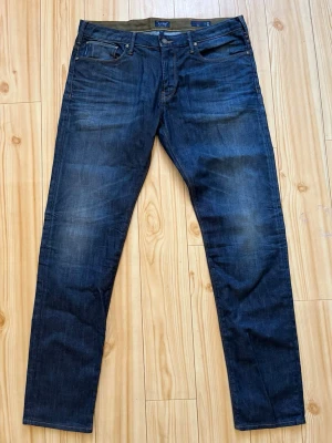 Mörkblå slim jeans från Armani Jeans - Snygga mörkblå slim fit jeans från Armani Jeans med klassiska fem fickor och kontrastsömmar. Jeansen har en lätt tvättad look och detaljer i metall. Perfekta för dig som gillar stilrena och tidlösa jeans i slitstarkt denimtyg.