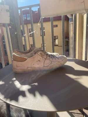 Phillipe model  - Säljer ett par vita sneakers med beige hälpanel och klassisk låg siluett. Skorna har vita snören och diskreta håldetaljer på sidan. Tillverkade i slätt material som ser ut som läder. Perfekta för en clean och enkel stil. Låda finns inte så skorna kommer i en kartong! Därför är priset sänkt så mycket! Annars är dom i superfint skick och bara att använda.