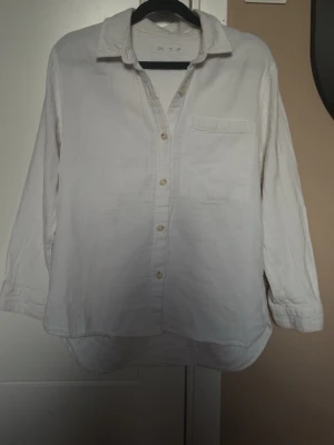 Vit skjorta från Zara - Vit skjorta från Zara med klassisk krage, bröstficka och knappar framtill. Skjortan har lång ärm och är tillverkad i ett mjukt material som känns skönt mot huden. Perfekt för en clean och stilren look.