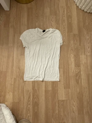 Vit basic t-shirt i bomull - En enkel vit t-shirt med korta ärmar och rund hals. Tillverkad i mjuk bomull och har en klassisk passform som funkar till det mesta. Perfekt att matcha med jeans eller shorts för en clean look.