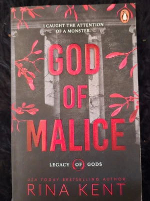 God of Malice av Rina Kent - En engelskspråkig pocketbok med titeln 'God of Malice' av Rina Kent. Omslaget är svart med röda och orange detaljer, inklusive växtmotiv och pelare. Boken ingår i serien 'Legacy of Gods' och har en modern, mystisk design.
