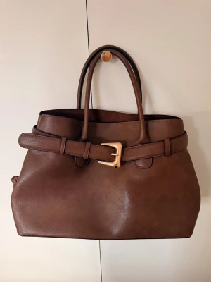 Brun handväska med bältdetalj - Intressekoll på denna superfina bruna väska. Väldigt rymlig och endast använd 1 gång. Perfekt till hösten!💕🍂