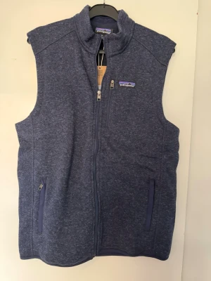 Patagonia väst  - Säljer en klassisk och stilren Patagonia Better Sweater fleeceväst i herrmodell. Färgen är en mycket snygg, melerad mörkblå nyans (New Navy). Storlek M. Den är ny. 
