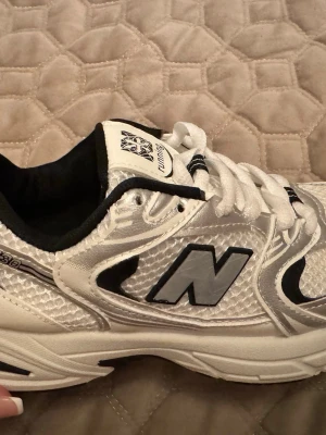 Vita sneakers - Snygga vita sneakers med silvriga och svarta detaljer. Skorna har en klassisk låg siluett, mesh och syntetmaterial i ovandelen samt en bekväm sula. Perfekta för dig som gillar retrostil och sportig vibe.