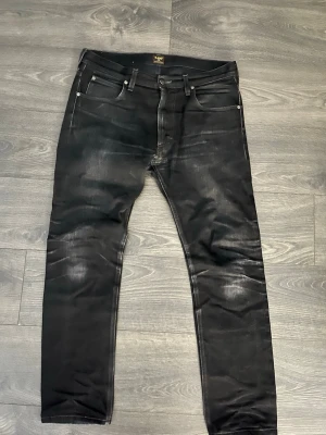 Lee Jeans - Säljer ett par svarta jeans från Lee med snygga slitningar och tvättade detaljer. Klassisk femficksmodell med raka ben och normal midja. Perfekta för en avslappnad och trendig stil. Har blivit laggade men inget som syns när man använder dem