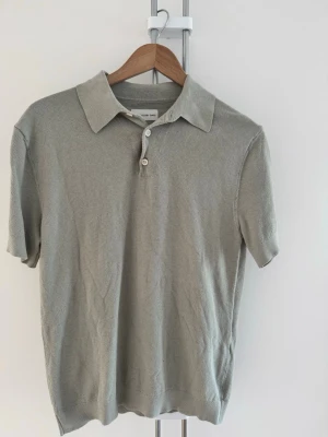 Piké - These Glory Days - Grå stickad polotopp med klassisk krage och två knappar framtill. Kortärmad modell i mjukt material som ger en avslappnad men ändå stilren look.