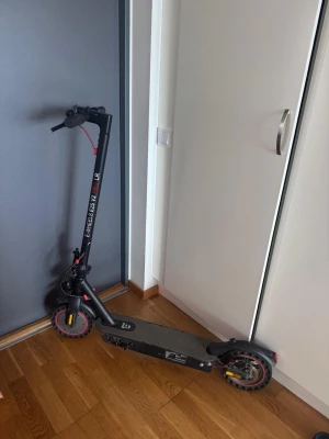 Elscooter E-Wheels E25 V2 PRO LR - Säljer en svart elscooter E-Wheels E25 V2 PRO LR med röda detaljer. Scootern har robust ram i metall, bred fotplatta och luftfyllda däck med röd kant. Perfekt för smidig transport i stan och enkel att fälla ihop när den inte används.