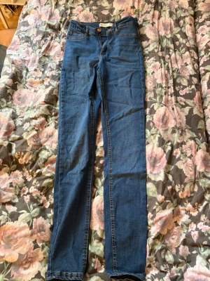 Mörkblå skinny jeans med hög midja - Snygga mörkblå skinny jeans med hög midja och klassisk femficksdesign. Jeansen har smal passform och är tillverkade i stretchigt denimtyg för extra komfort. Perfekta att matcha med en crop top eller hoodie.