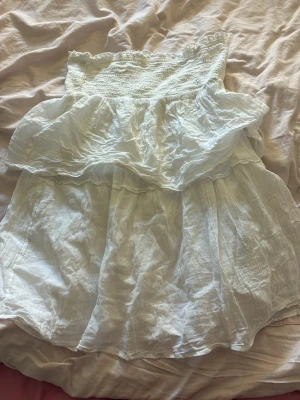 Vit volangkjol från Gina Tricot - Supersöt vit kjol från Gina Tricot med smock i midjan och dubbla volanger upptill. Kjolen är gjord i ett tunt, luftigt tyg som känns perfekt för sommaren. Den har en avslappnad passform och romantisk känsla. Jag köpte den på Young men de står ingen storlek men de kan användas som klänning eller kjol 