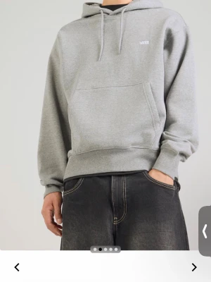 Grå hoodie från Vans med huva - Snygg grå hoodie från Vans med klassisk huva och dragsnören. Tröjan har en stor magficka och diskret Vans-logga på bröstet. Tillverkad i mjukt material som känns skönt mot huden. Perfekt för en avslappnad och stilren look.