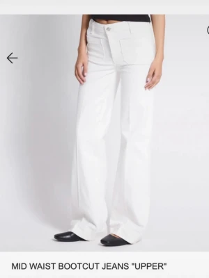 Vita jeans med fickor - Säljer ett par vita jeans med medelhög midja och stora fickor framtill. Jeansen har en klassisk femficksdesign och stängs med knapp och dragkedja. Perfekta för en clean och trendig look.