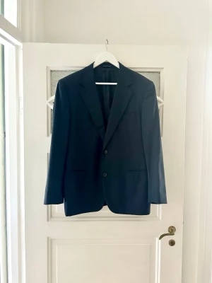 Canali kavaj  - Snygg mörkblå kavaj med två knappar framtill och klassisk krage. Tillverkad i Italien och har en stilren, tidlös design som passar till många olika looks. Perfekt för dig som vill ha en enkel men elegant kavaj.