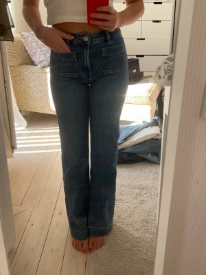 Utsvängda jeans med fickor - Säljer mina supersnygga midrise bootcut jeans med fickor där fram från bikbok/never denim. Köptes i vintras och de finns inte längre kvar. Säljer för 600kr. De är i storlek 24-30 men de är relativt stretchiga så passar även mig som har 25 i midjan. Innerbenslängden är 72-73 cm. 