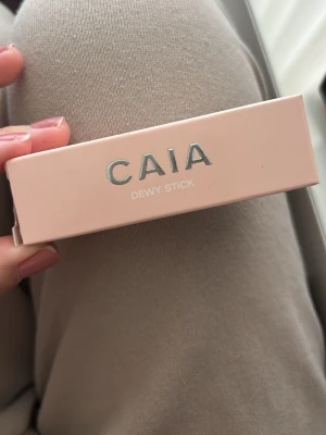 CAIA Dewy Stick highlighter - Highlighter i stickformat från CAIA med krämig formula. Kommer i en ljusrosa förpackning med silvrig text. Ger en fräsch, daggig finish och är enkel att applicera direkt på huden. Perfekt för att skapa glow på kindben, näsrygg och amorbåge.