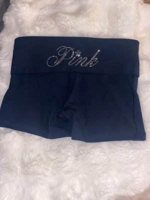 HOTPANTS PINK, Victorias Secret  - Säljer ett par marinblå hotpants från Pink med bred midja och glittrande strassdetalj baktill. Shortsen har en tight passform och är perfekta för en avslappnad och trendig look. Aldrig använda💓💓💓💓💓