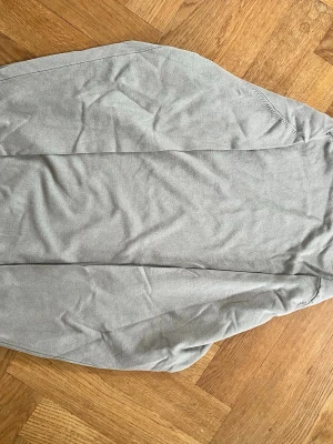 Ljusgrå långärmad tröja - En enkel och stilren ljusgrå långärmad tröja med rund hals och ribbade muddar (turtleneck).  Tröjan är tillverkad i ett mjukt, tunt material som passar perfekt till vardagslooken. Tröjan har aldrig använts. 
