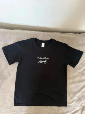 Rick Owens  - Snygg svart t-shirt med vit textprint både fram och bak i handskriftsstil. Klassisk rund hals och korta ärmar. Tillverkad i mjuk bomull som känns skön mot huden. Perfekt för dig som gillar stilrena plagg med en twist.