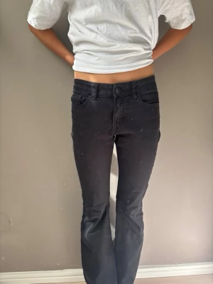 Svarta bootcut jeans - Säljer ett par svarta bootcut jeans med klassisk femficksdesign och normal passform. Jeansen har en enkel look utan synliga detaljer och är perfekta för en clean och stilren outfit.
