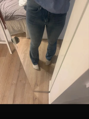 Blå bootcut jeans med pärldetaljer - Säljer ett par ljusblå bootcut jeans med snygga pärldetaljer på bakfickorna. Jeansen har klassisk femficksmodell, normal midja och är tillverkade i ett stretchigt denimtyg för skön passform. Perfekta för dig som gillar en avslappnad men trendig look.