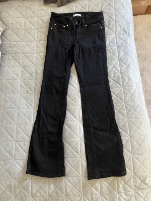 Svarta bootcut jeans - Säljer ett par svarta bootcut jeans med klassisk femficksmodell och normal midja. Jeansen har utsvängda ben och är tillverkade i ett mjukt denimtyg som ger en snygg siluett. Perfekta för dig som gillar en tidlös och trendig look.