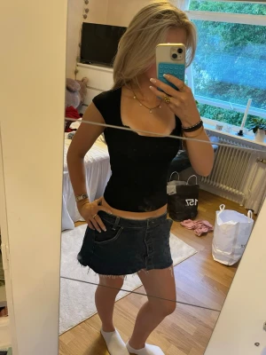 Svart croppad topp med squere-ringning - Säljer en svart croppad topp med djup v-ringning och korta ärmar. Toppen har en tight passform och är perfekt att styla med jeans eller kjol. Tillverkad i mjukt bomullsmaterial som känns skönt mot huden.