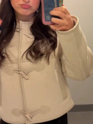 Beige teddyjacka med snörning RESERVED - Säljer en beige teddyjacka från Reserved med snygga snörningsdetaljer framtill. Jackan har rundad krage, två fickor och en loose passform som ger en chill vibe. Perfekt för dig som vill ha en mysig och trendig jacka till hösten.