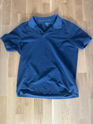 Marinblå pikétröja från Gant - Klassisk marinblå pikétröja från Gant med krage och korta ärmar. Tillverkad i mjuk bomull som känns skön mot huden. Perfekt till jeans eller shorts för en avslappnad stil.