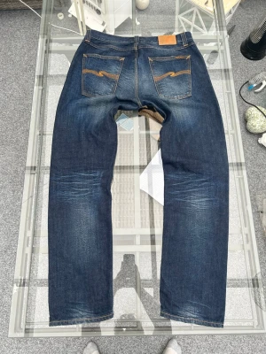 Nudie Jeans Sharp Bengt W34/L32 - Säljer ett par Nudie Jeans Sharp Bengt i storlek W34/L32. Tillverkade i 100% ekologisk bomull i en mörk indigo tvätt med naturlig fading som ger en snygg denimkaraktär.  * Storlek: W34/L32 * Modell: Sharp Bengt * Färg: Mörkblå (Indigo) * Material: 100% Organic Cotton * Skick: Fint begagnat skick, se bilder.  En tidlös modell som passar perfekt till både sneakers och boots. Skickas snabbt eller möts upp vid behov.