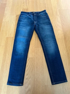 Jack and Jones tapered Mike - Marinblå jeans från Jack and Jones i modellen tapered Mike. Jeansen är i storlek W30 L32, och är i mycket bra skick, enda slitaget är att Jack and Jones lappen bak har lossnat lite (se bild 3), men det går lätt att sy ihop igen. Hör av er vid frågor 