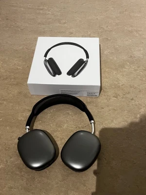 Apple AirPods Max hörlurar svart - Snygga Apple AirPods Max i svart med stilren design och mjuka öronkuddar. Hörlurarna har en metallbåge och meshband för extra komfort. Perfekta för musik, gaming eller film med grym ljudkvalitet och aktiv brusreducering.