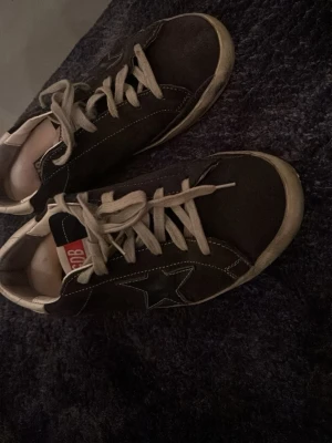 Mörkblå golden goose  - Snygga mörkblå sneakers från Golden goose med vit sula och vita skosnören. Skorna har en tydlig stjärndetalj på sidan och kontrastsömmar. Klassisk låg modell som passar till det mesta. Materialet är mocka