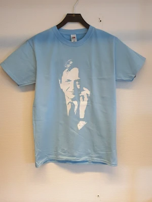 Ljusblå t-shirt med Olof Palme tryck Storlek smal - Ljusblå t-shirt med vitt tryck av Palme . Klassisk rund halsringning och korta ärmar. Tillverkad i mjuk bomull, perfekt för en avslappnad stil.
