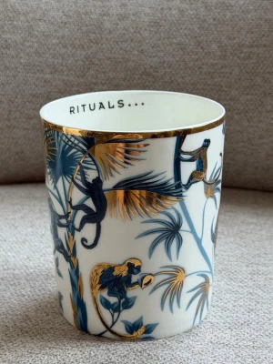 Rituals Luxury Candle Holder “Wild Jungle” Fine Bone China - Exklusiv ljushållare från RITUALS Private Collection – Wild Jungle. Tillverkad i Fine Bone China med eleganta detaljer i äkta 24K guld. Ursprungligen designad för Rituals refill-doftljus men passar även perfekt som inredningsdetalj, liten vas eller förvaring.   Mycket fint skick utan sprickor eller nagg. Finns inte längre i ordinarie sortiment.  - Original från Rituals - Fine Bone China - Lyxig design med 24k gulddekor - Originalpris: 499 kr Perfekt för dig som samlar på Private Collection. 
