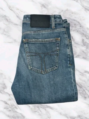 Tiger Of Sweden Ljusblåa Jeans  - Säljer ett par klassiska blå jeans med rak passform och snygga kontrastsömmar. Jeansen har en enkel bakficka och är tillverkade i ett slitstarkt denimtyg. Perfekta för en avslappnad och trendig look. W26 L32